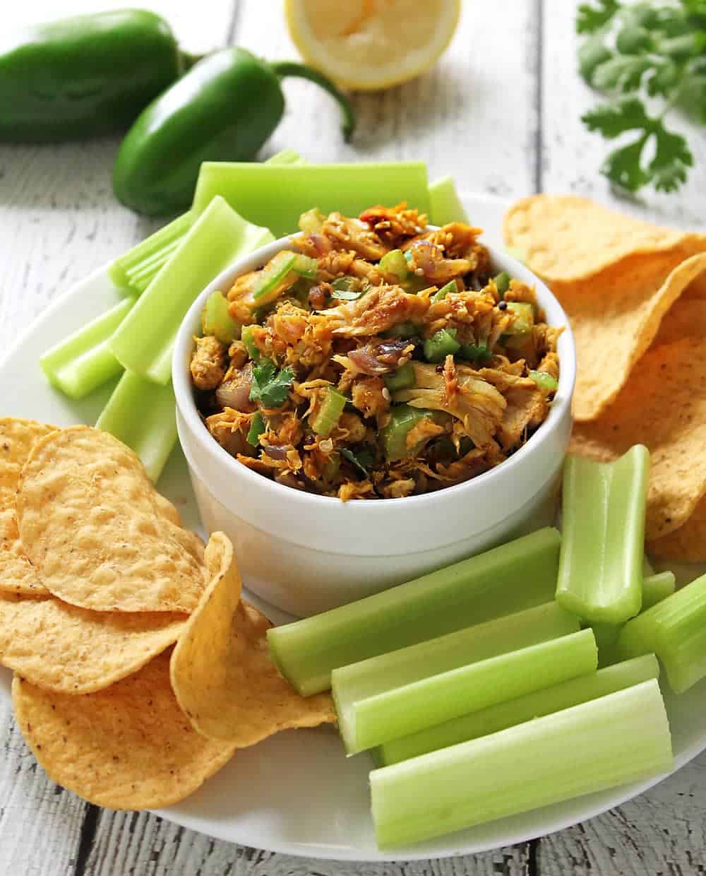 Warm Tuna Salad in a bowl surrounded with celery and chips.