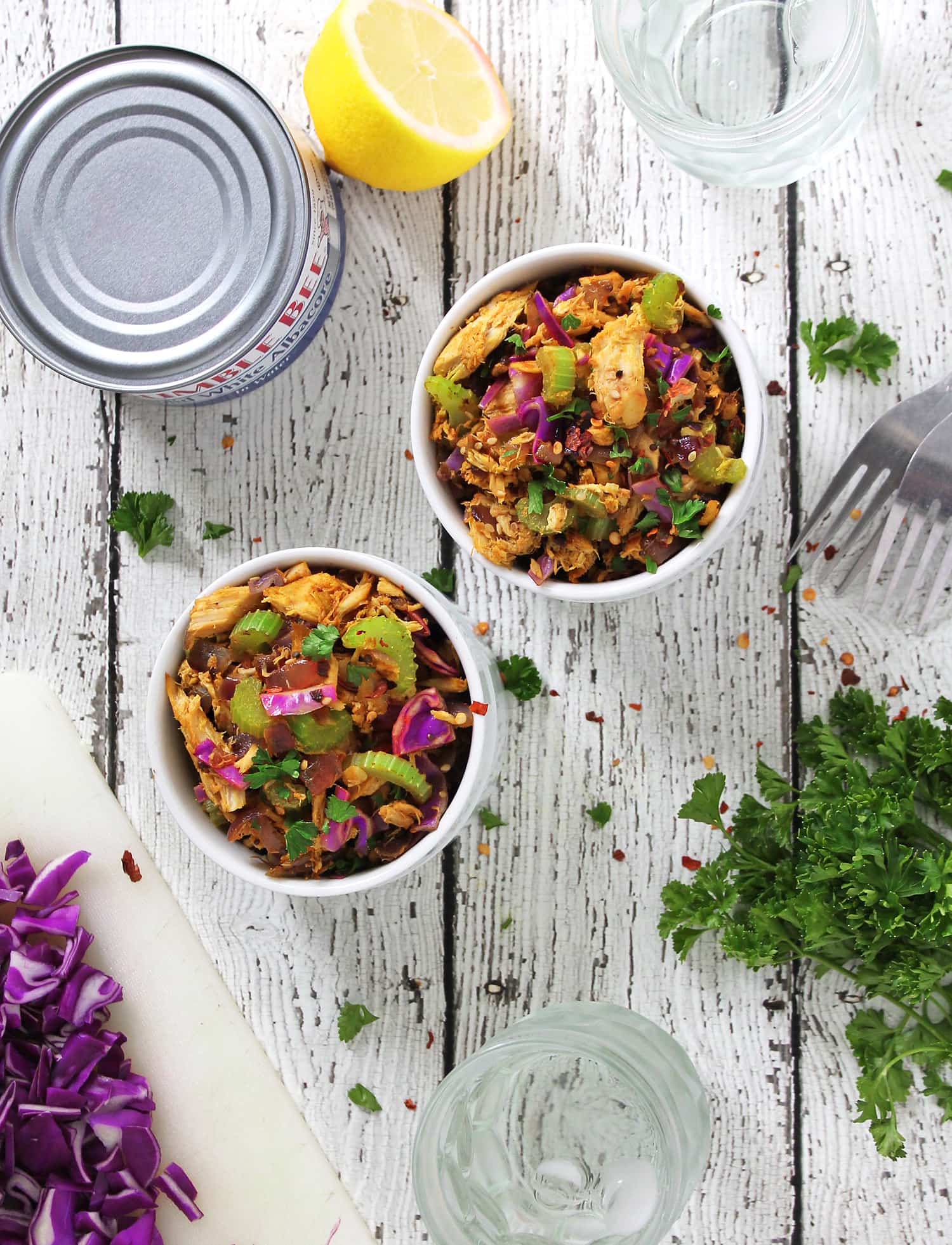 Warm Tuna Salad in two bowls with lemon and red cabbage on a cutting board