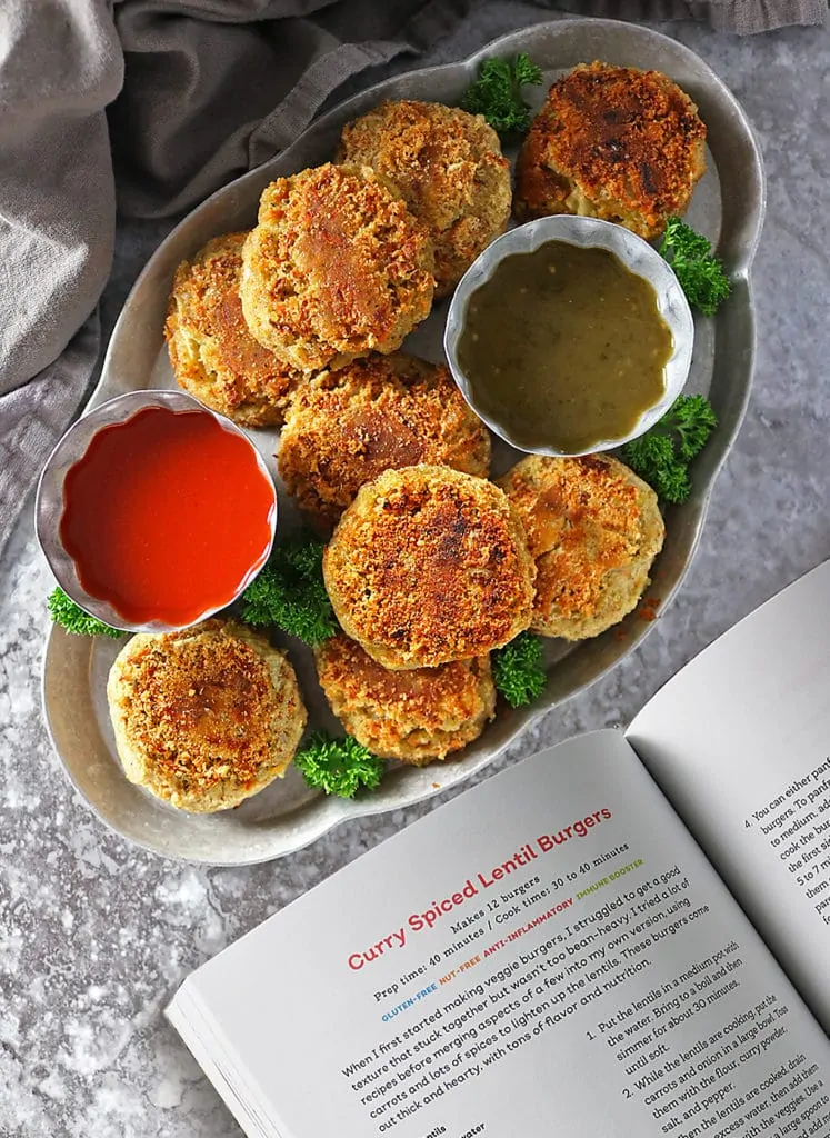 Overhead photo os angled container with Lentil Burgers and dipping sauces with napkin with open cookbook