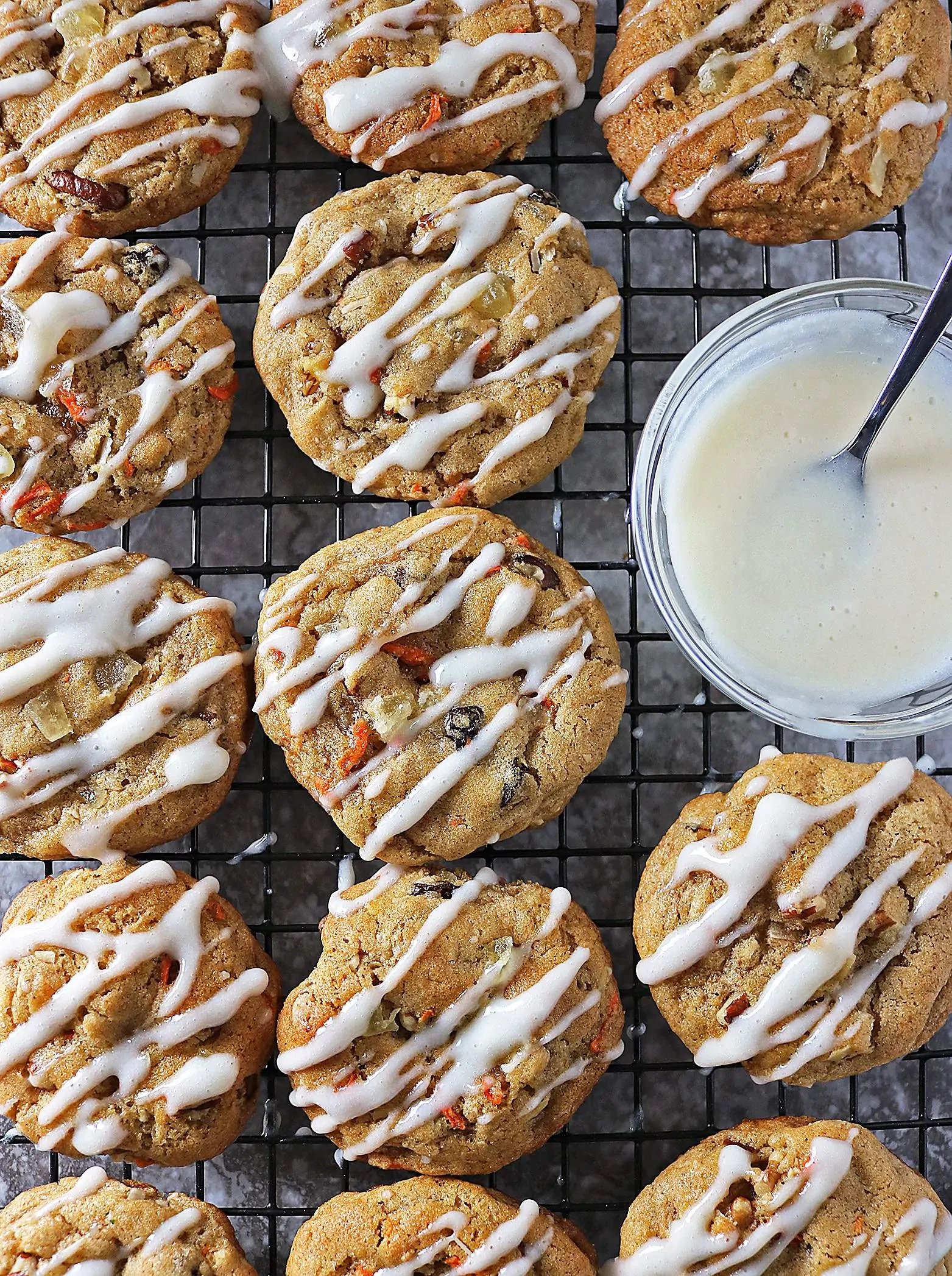 Chock full of carrots, walnuts, raisins, cardamom, cinnamon and candied pineapple, these Carrot Cake Cookies with Cream Cheese Drizzle are heavy on flavor.