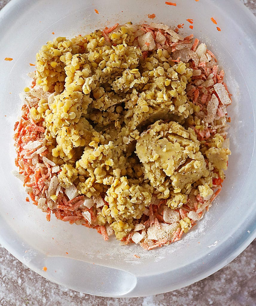 Mixing cooked lentils with carrots, curry and flour in a bowl.