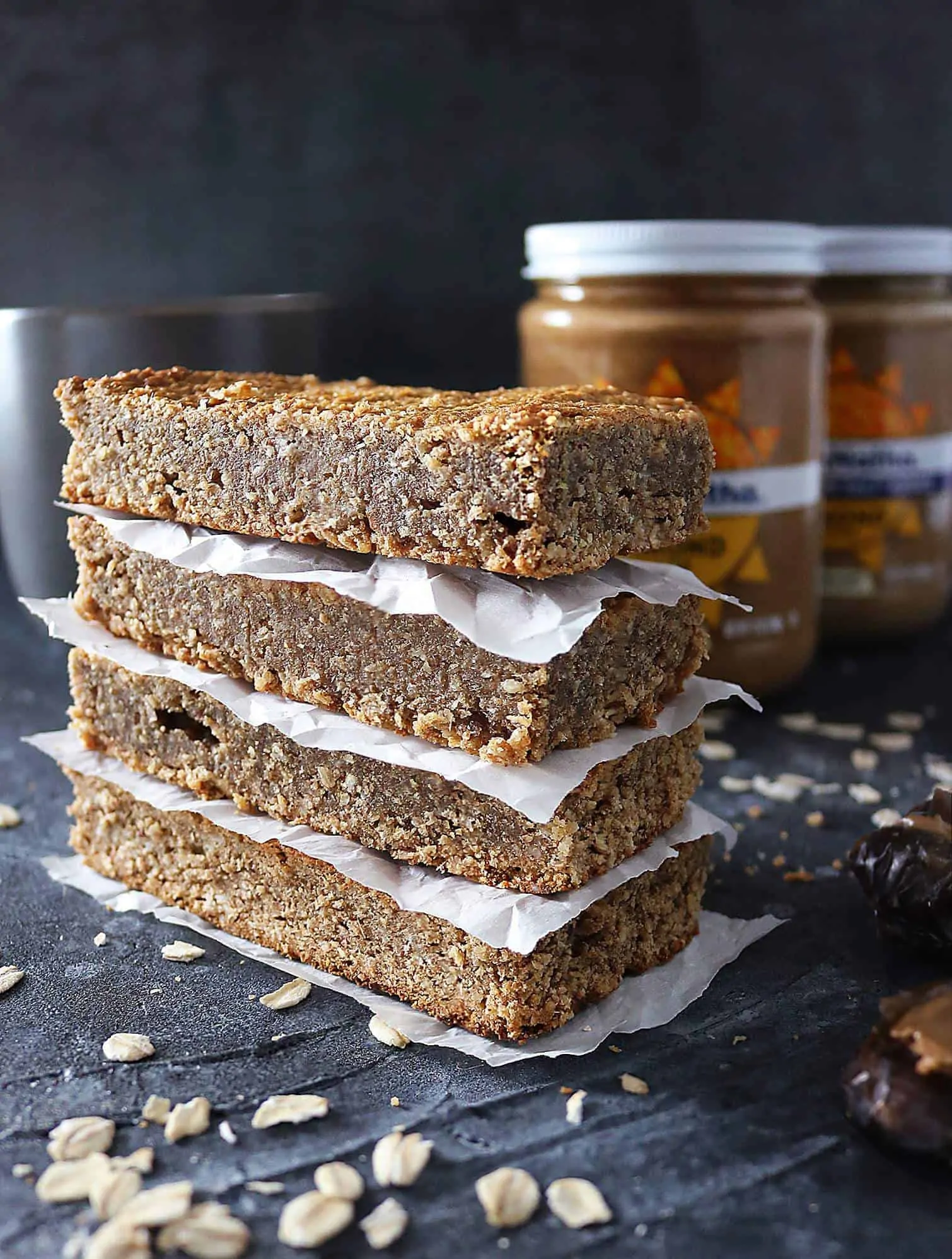 Stack of four Date Almond Bars with almond butter jars in the background.