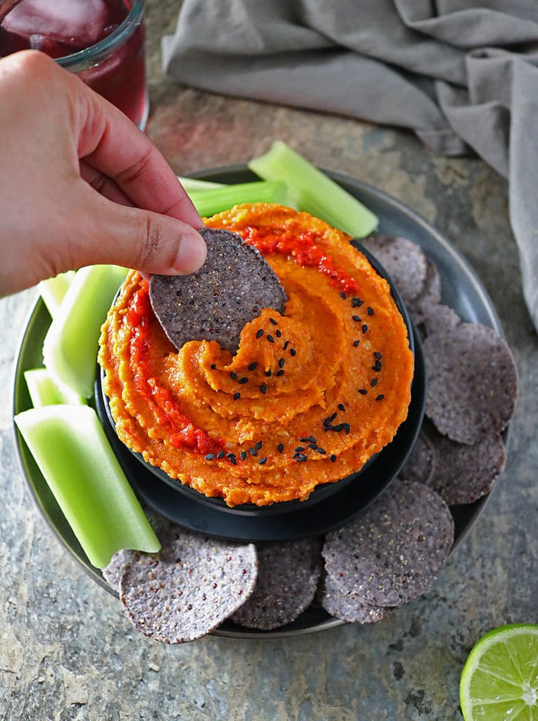 Overhead view of Roasted Butternut Squash Dip with chip in it and chips and veggies on plate.