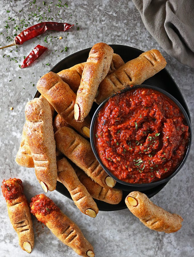 Overhead view of bowl of Roasted Red Pepper & Red Wine Dip and Whole Wheat Finger Breadsticks scattered around