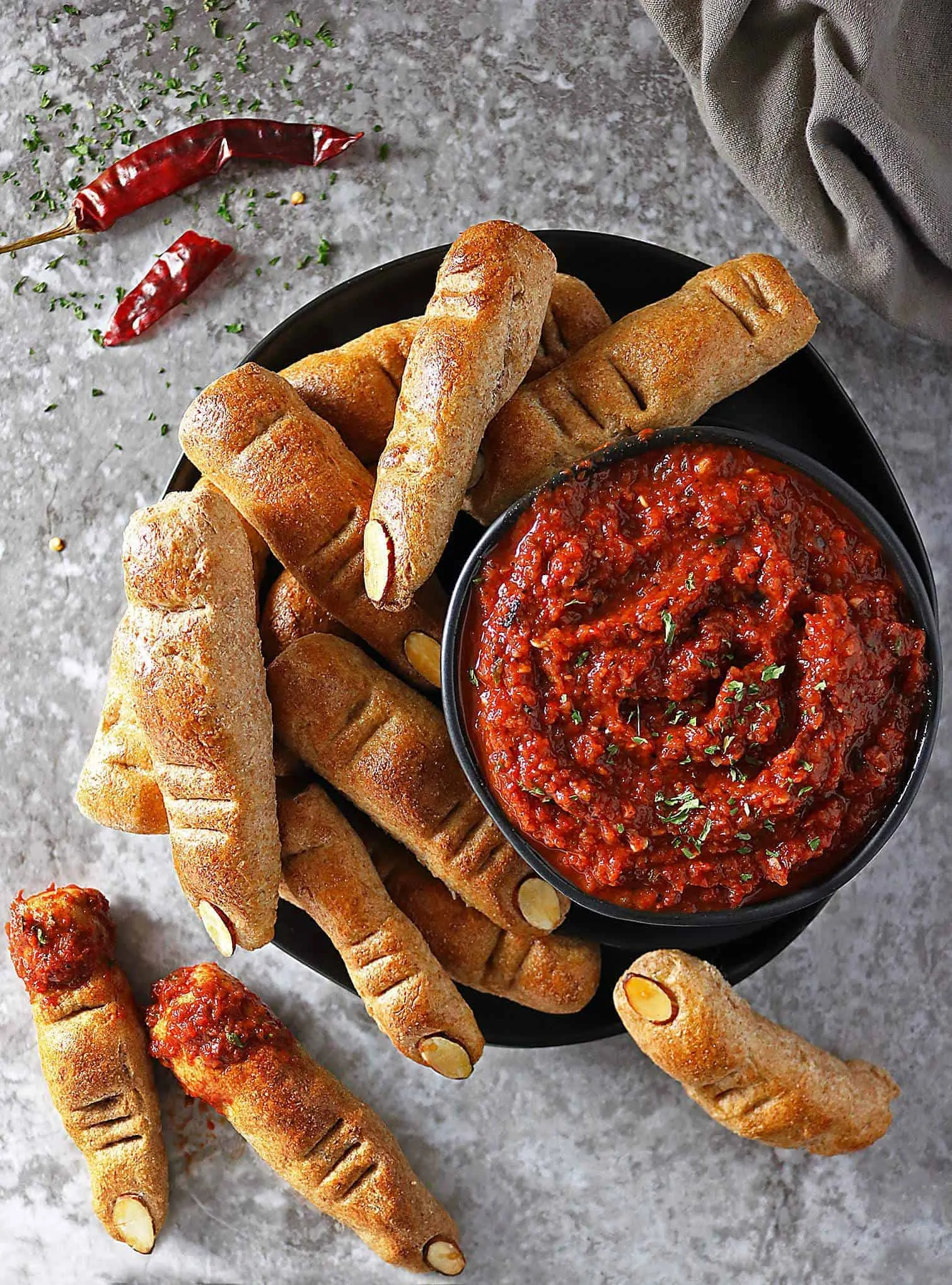 Overhead view of bowl of Roasted Red Pepper & Red Wine Dip and Whole Wheat Finger Breadsticks scattered around