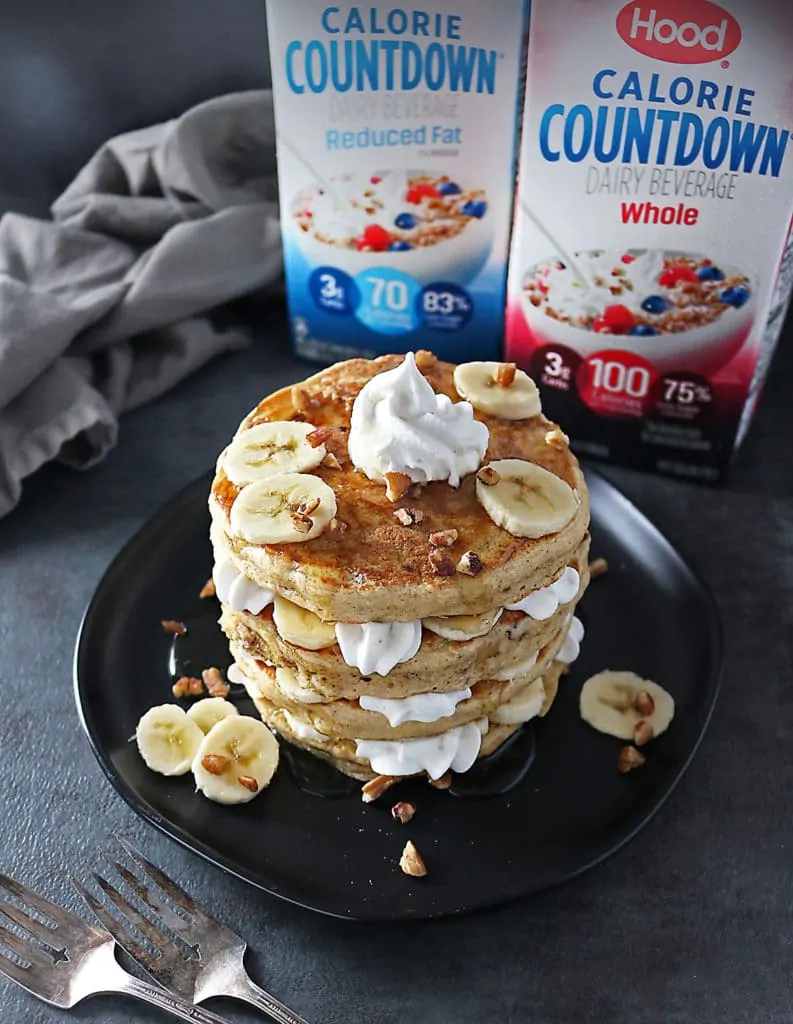 Stack of Pecan Banana Pancakes with layers of bananas and whipped cream and Hood Calorie Countdown in the background