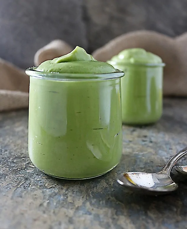 Photo with two glass pots of avocado pudding with spoons