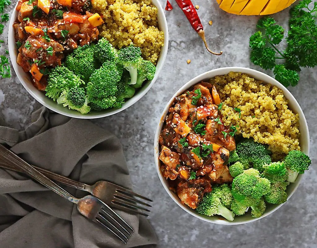 Two bowls of mango chicken with turmeric quinoa and steamed broccoli