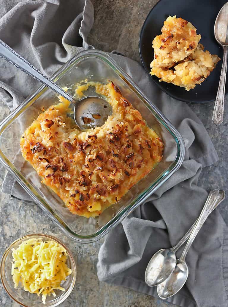 Overhead photo of plate with a scoop of pineapple casserole and glass container with remaining pineapple casserole in it.