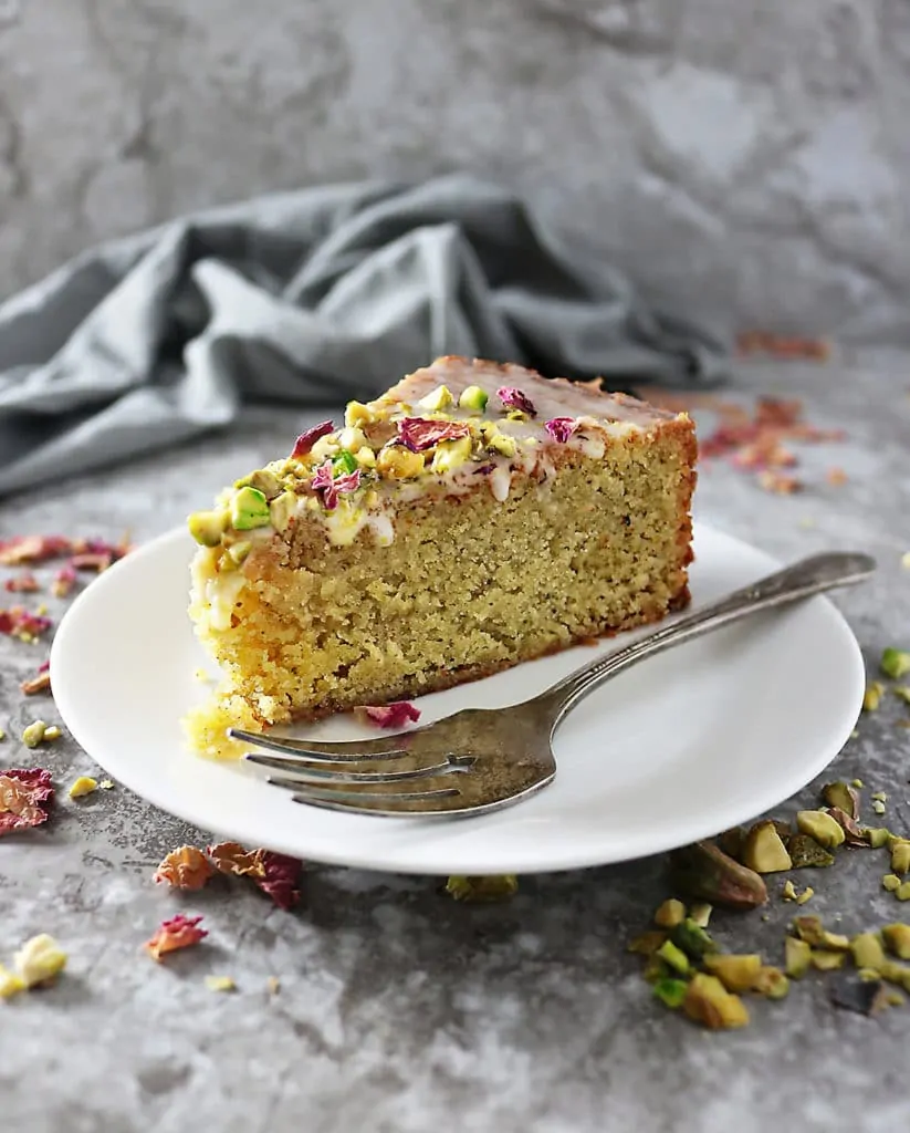 A Slice of Ottolenghi's Pistachio Rose Cake on a plate with a fork