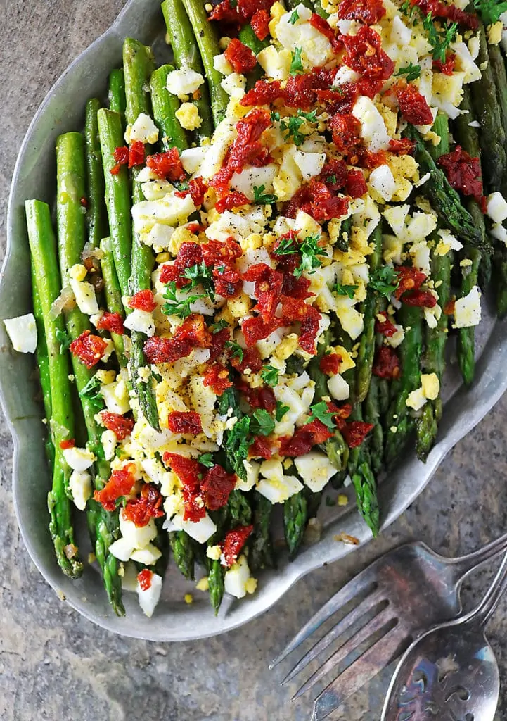 Overhead photo of Sauteed Asparagus, boiled egg and sundried tomatoes in a platter