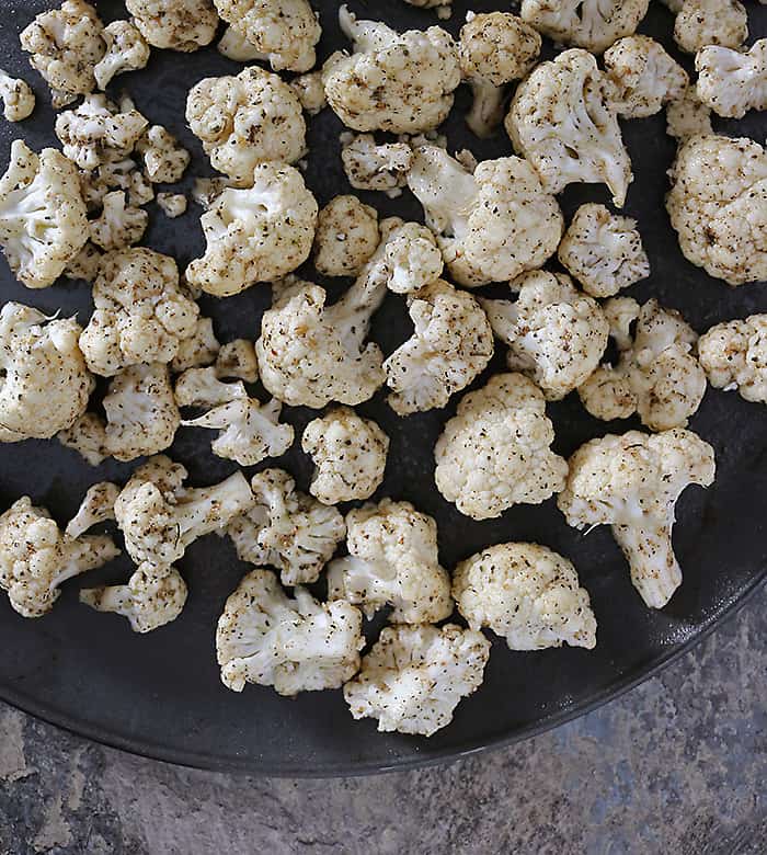 Cauliflower coated in olive oil oregano coriander mix on baking tray