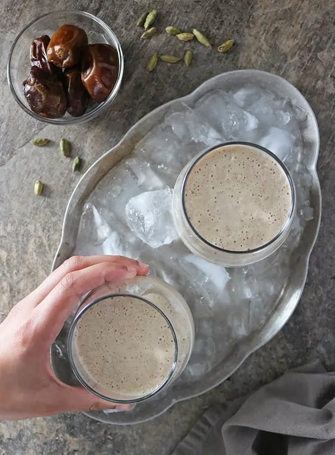 Overhead photo of hand reaching for 1 of 2 glasses with date shake in them