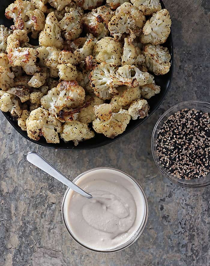 Overhead photo of roasted cauliflower with tahini sauce and sesame seeds