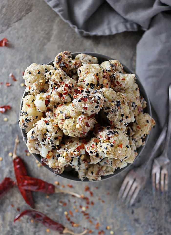 Overhead photo of bowl with Sesame Cauliflower with dried chilis on the side