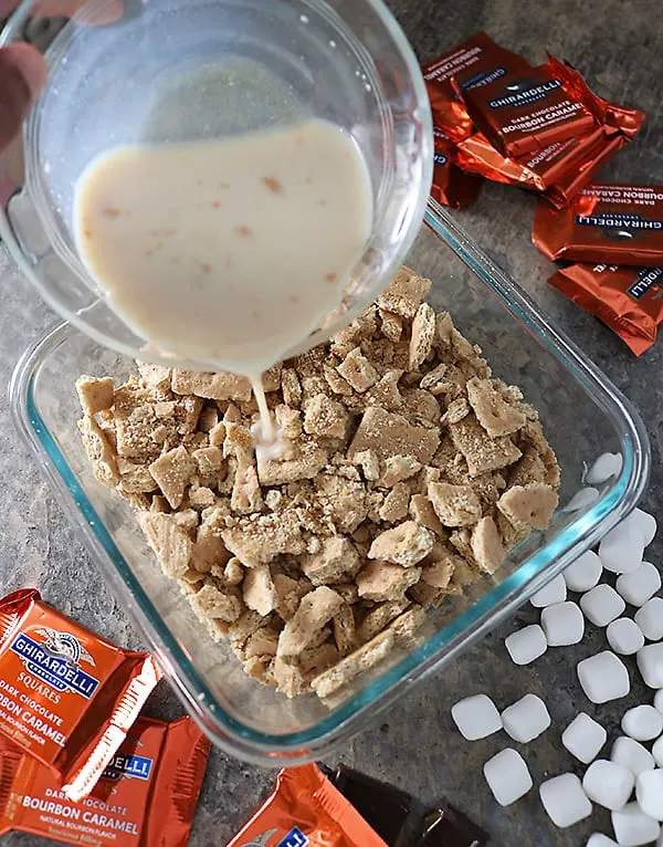 Bourbon Caramel Milk being poured on graham cracker smore base