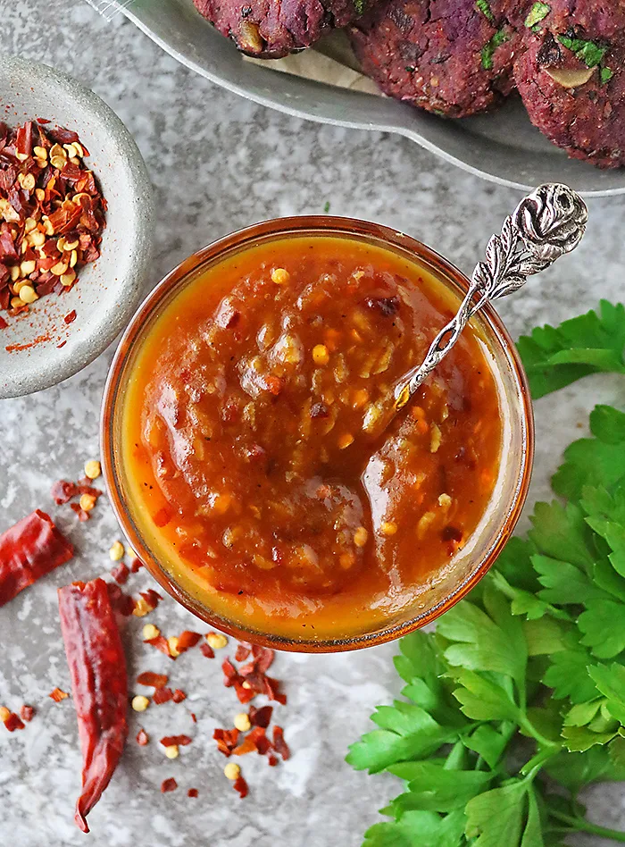 A jar with easy pumpkin chili sauce on a grey backgroumd.