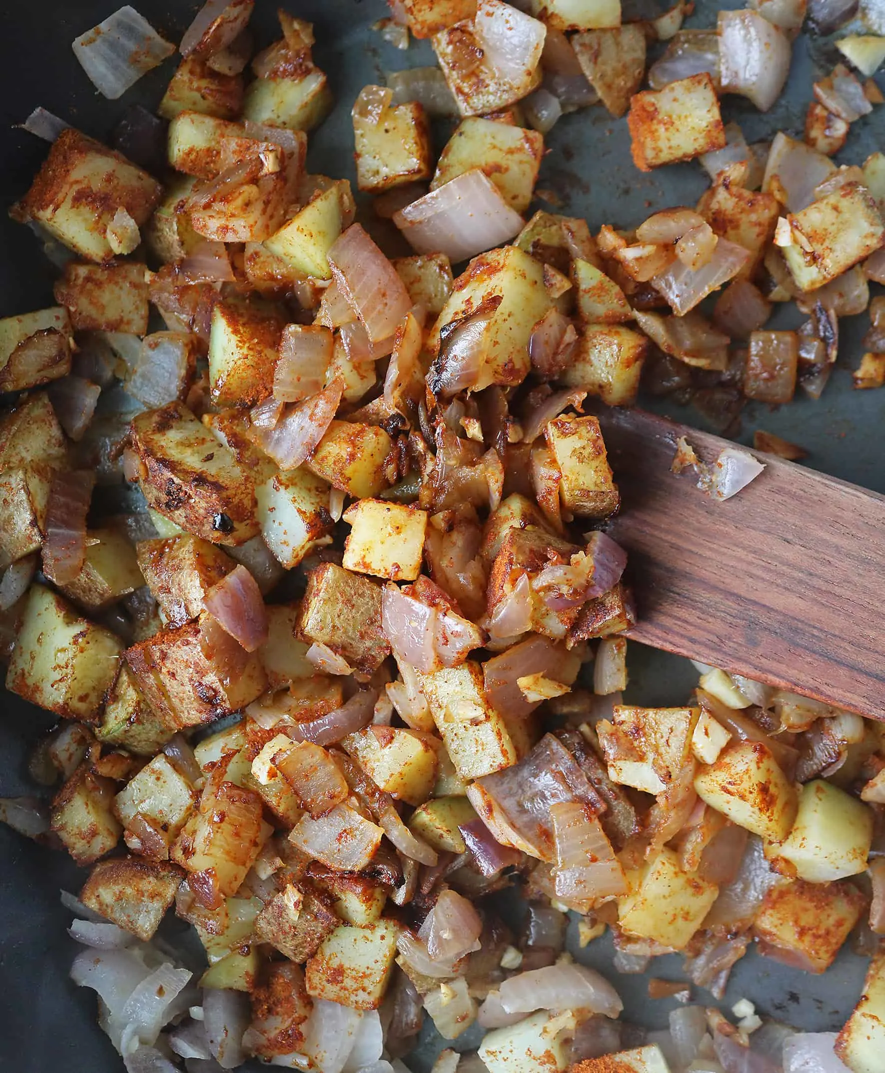 Cubed potatoes being sauteed with onions, garlic, ginger and Berbere seasoning.