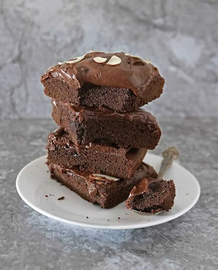 Slices of Dairy Free Chocolate cake with dairy free frosting stacked on top of each other.