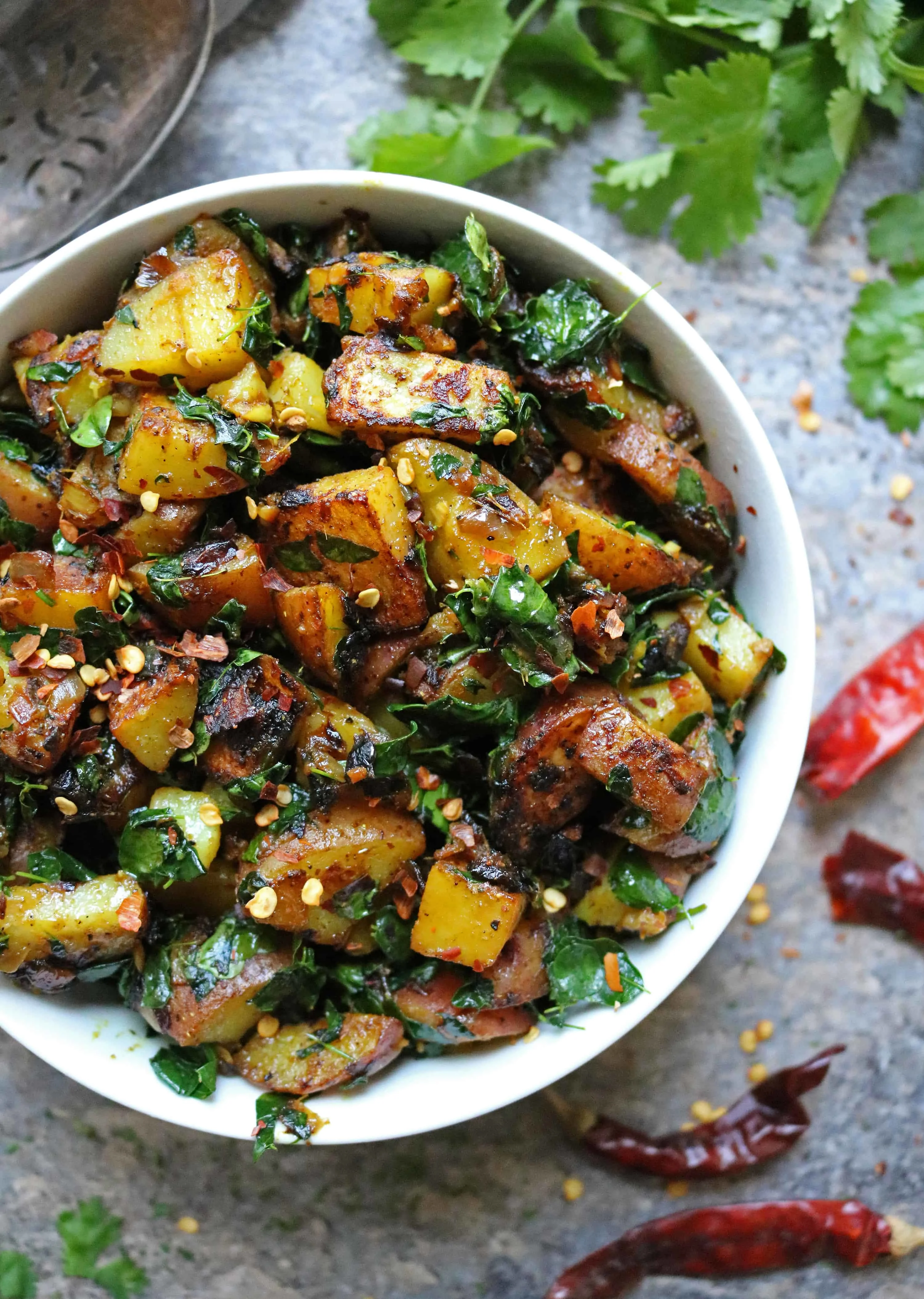 A close up of a bowl with moringa leaves cooked with potatoes to make a delicious, nutritious potato salad.