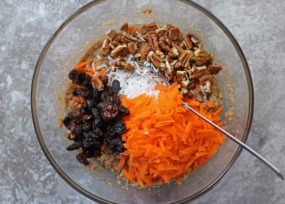 Mixing ingredients like carrots, raisins and walnuts for paleo carrot cake bars