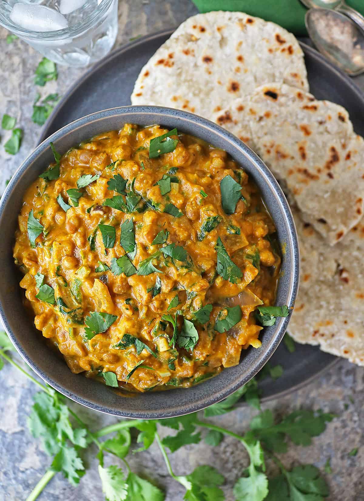 Easy vegan lentil curry in a bowl with Sri Lankan roti in a plate near by.