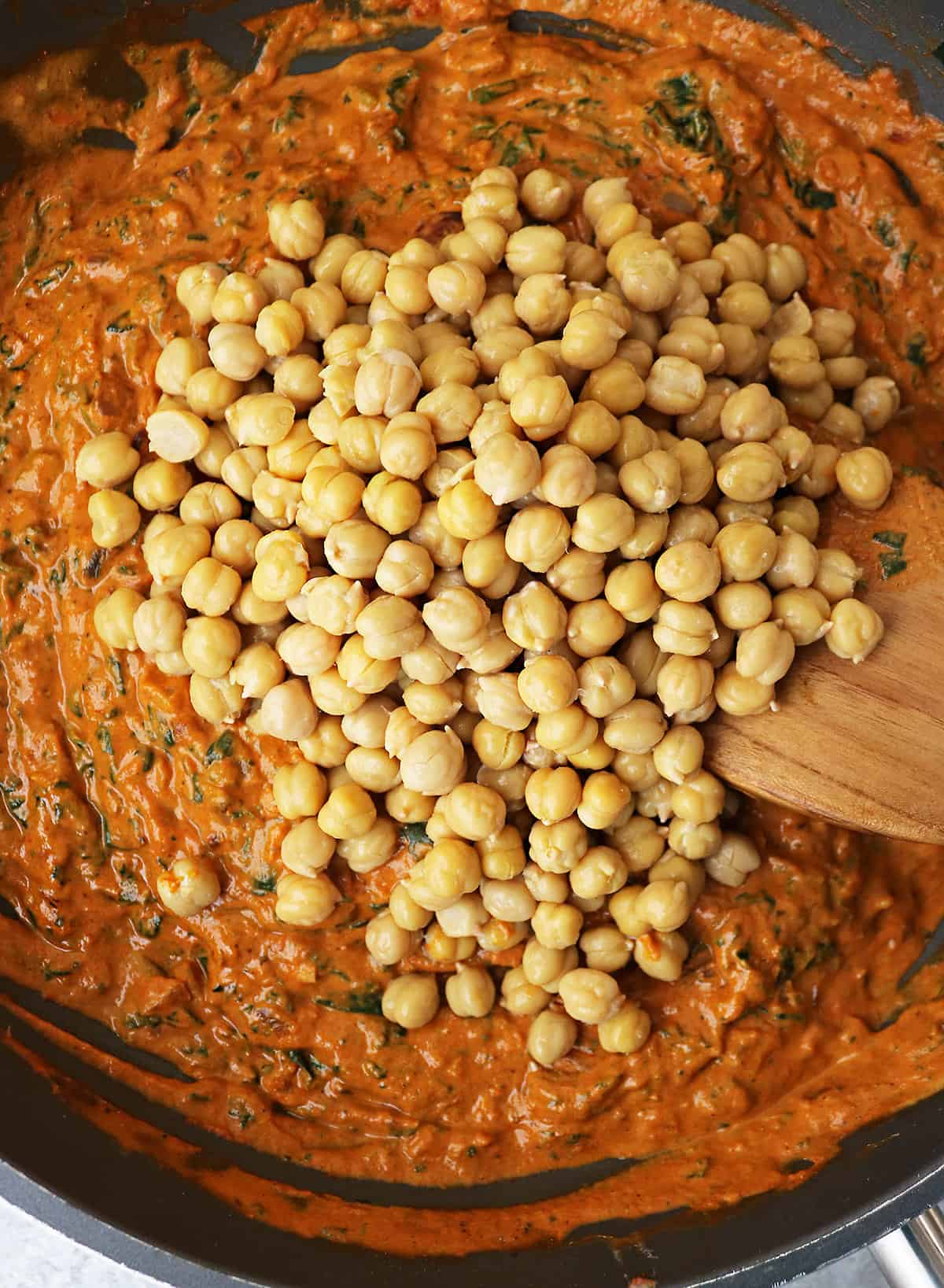 Adding chickpeas to tomato coconut- curry base in pan