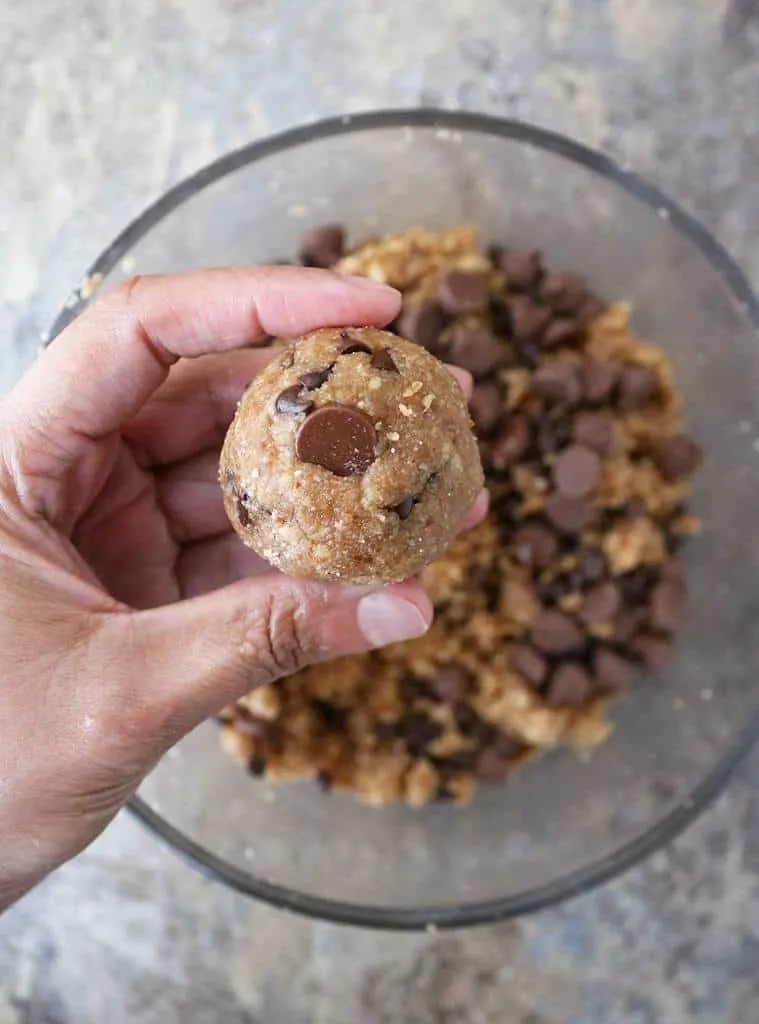 Making tasty egg free almond chocolate chip cookies by forming dough into a ball.