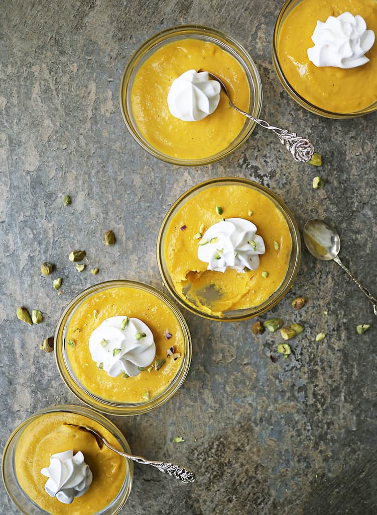 5 bowls of vegan mango custard - some with spoons and some without.