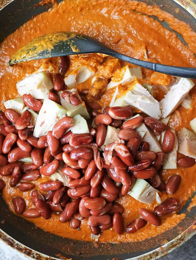 adding jackfruit and beans to creamy vegan curry sauce for jackfruit curry