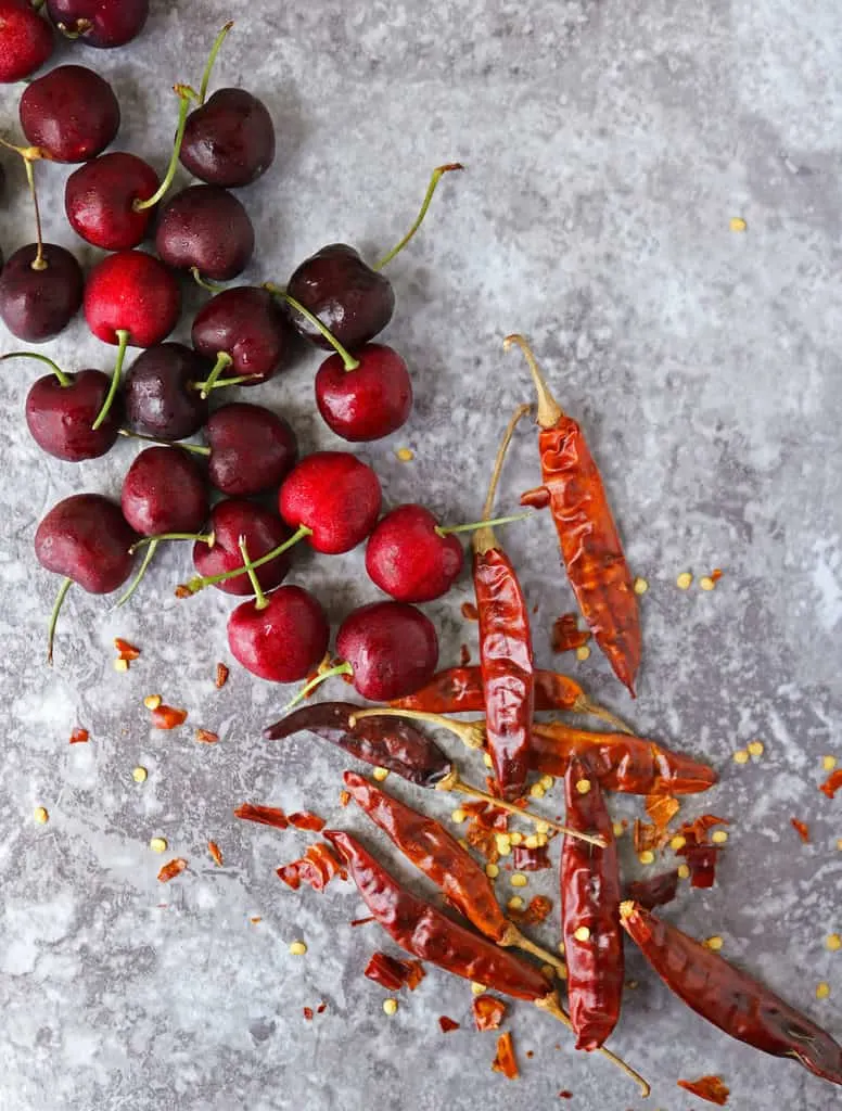 gray board with cherries and chilies