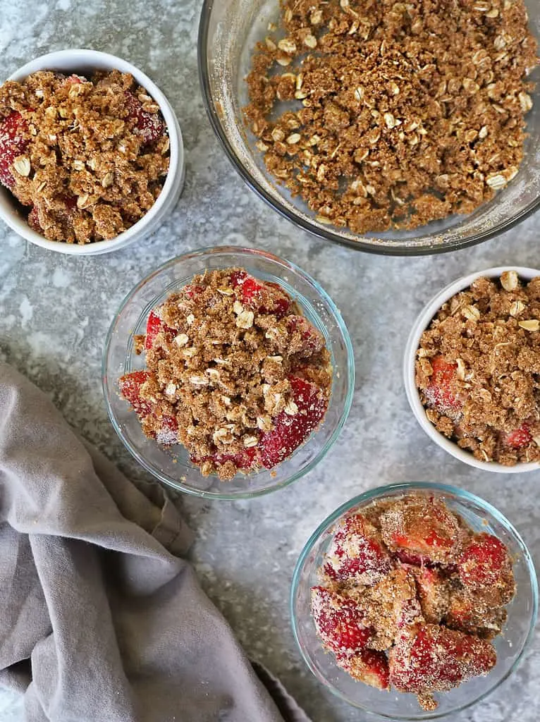 putting the crisp topping on the strawberry crisp