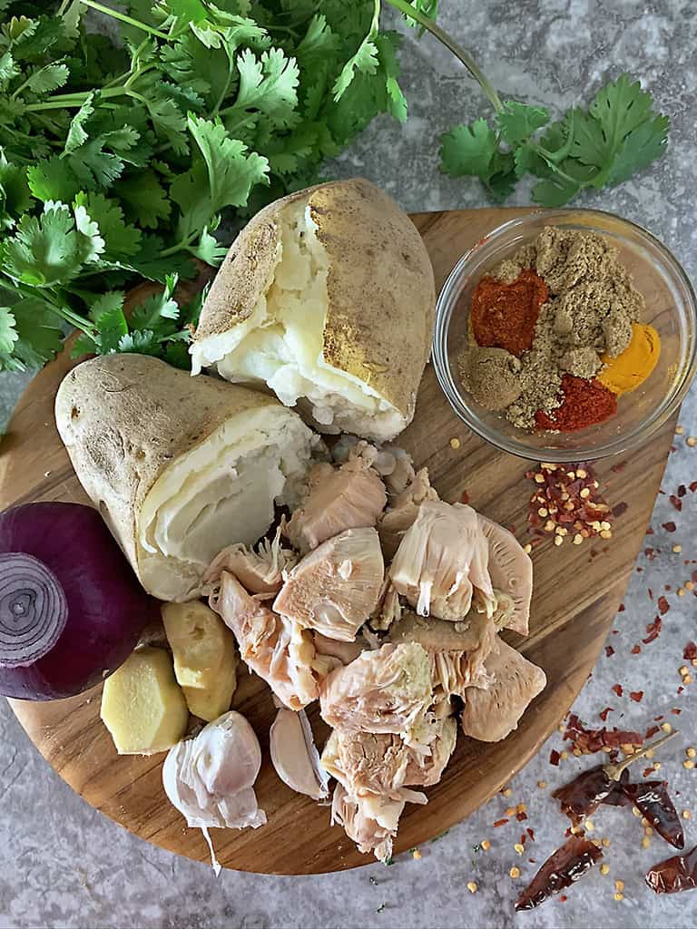 Ingredients to make jackfruit cakes on a wood cutting board.