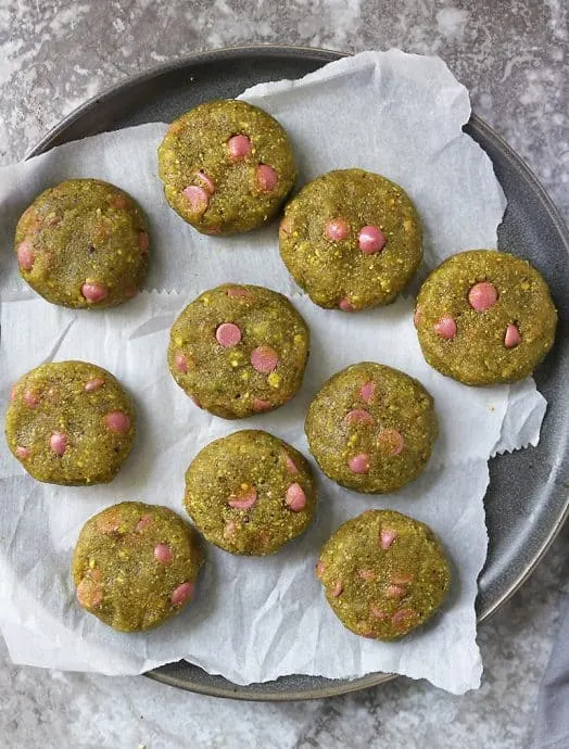 A plate of pistachio cookies with ruby chocolate ready to chill.