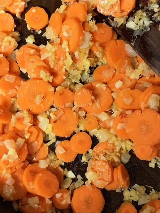 sauteing carrots, onions, ginger, garlic to make carrot curry