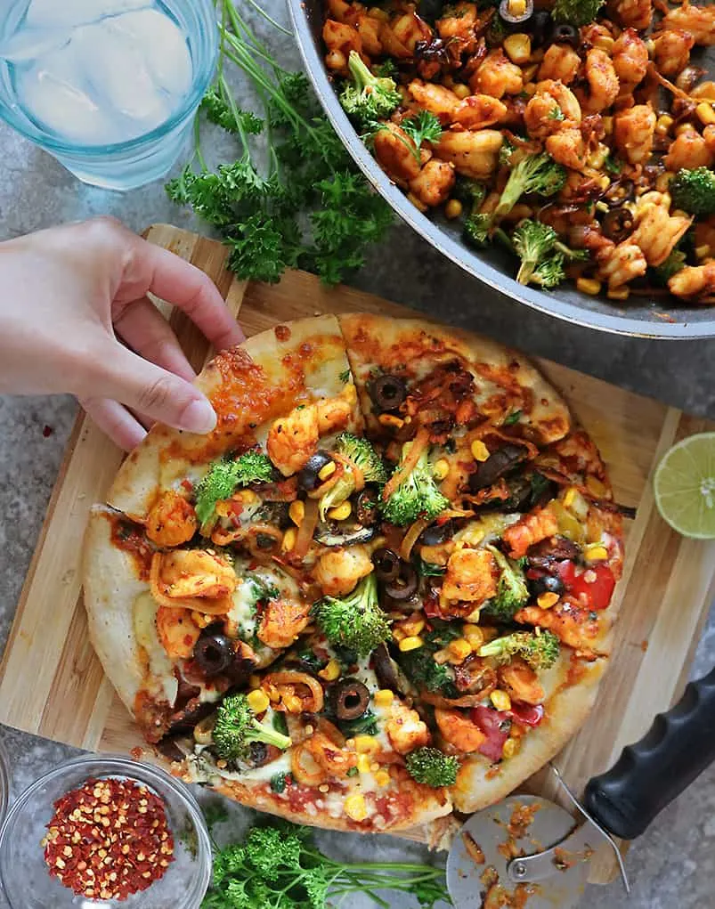 grabbing a slice of Shrimp Broccoli loaded Frozen Pizza From Sprouts