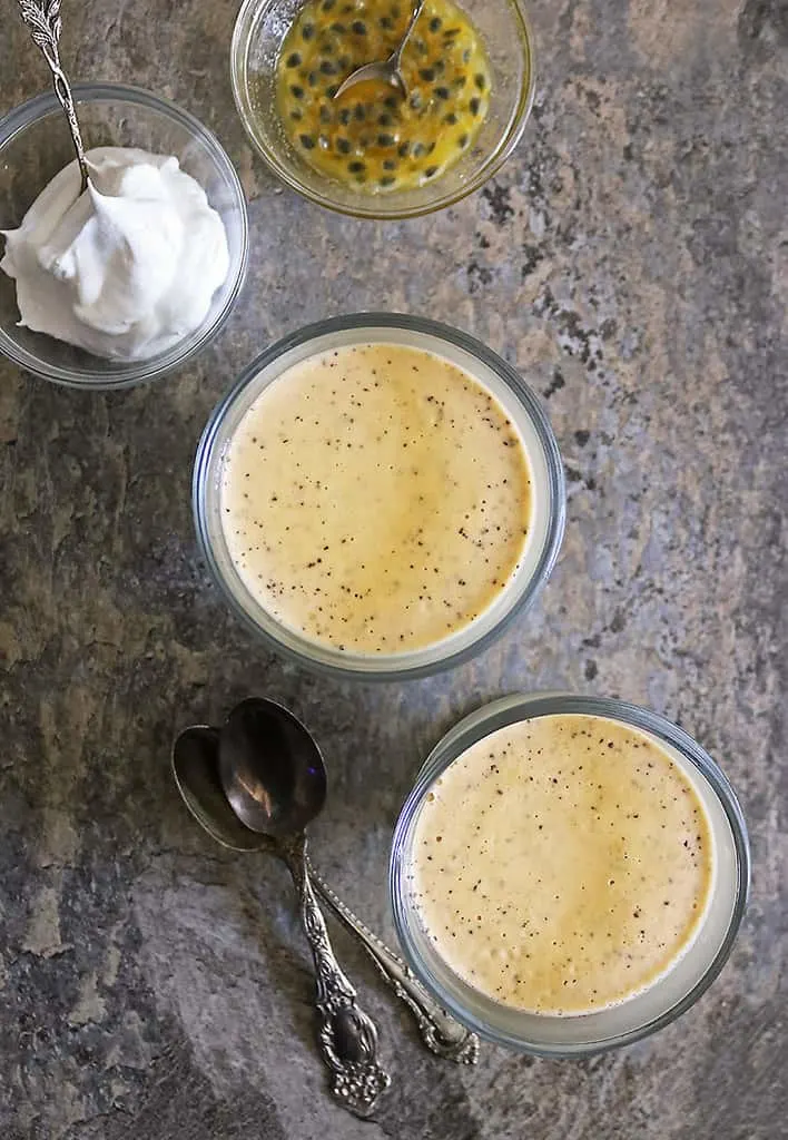 Tasty Vegan Passion fruit Mousse in 2 glass bowls with whipped coconut cream and passion fruit pulp.