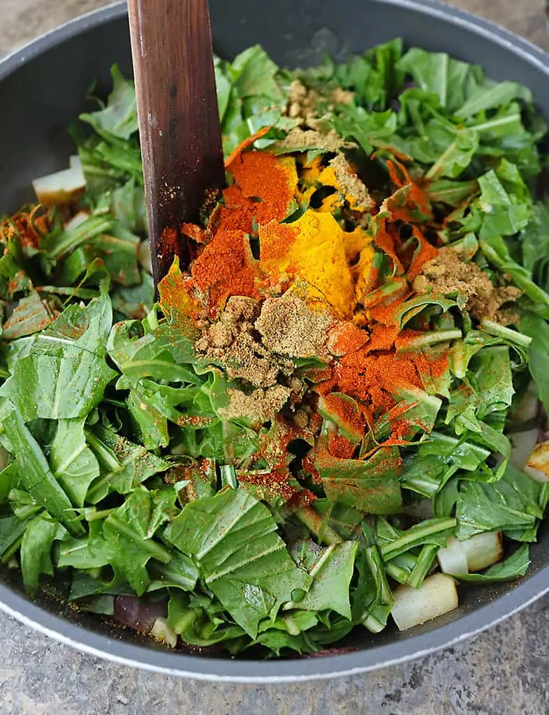 sauteeing dandelion greens and spices to make a healthy potato salad.