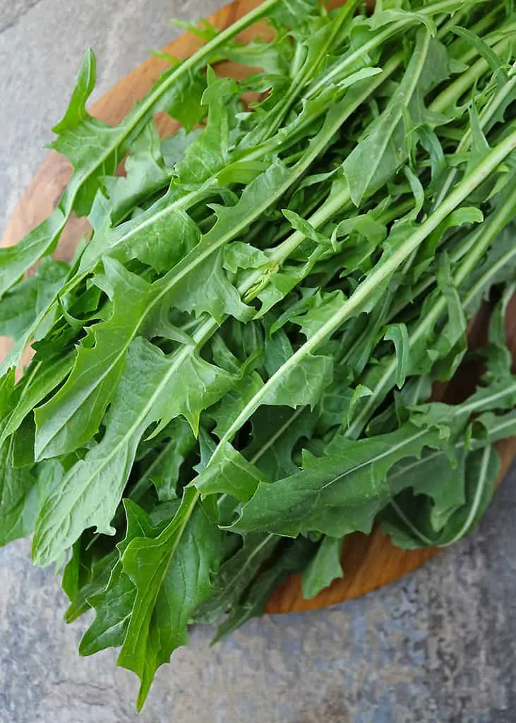 Fresh dandelion greens on a wooden platter.