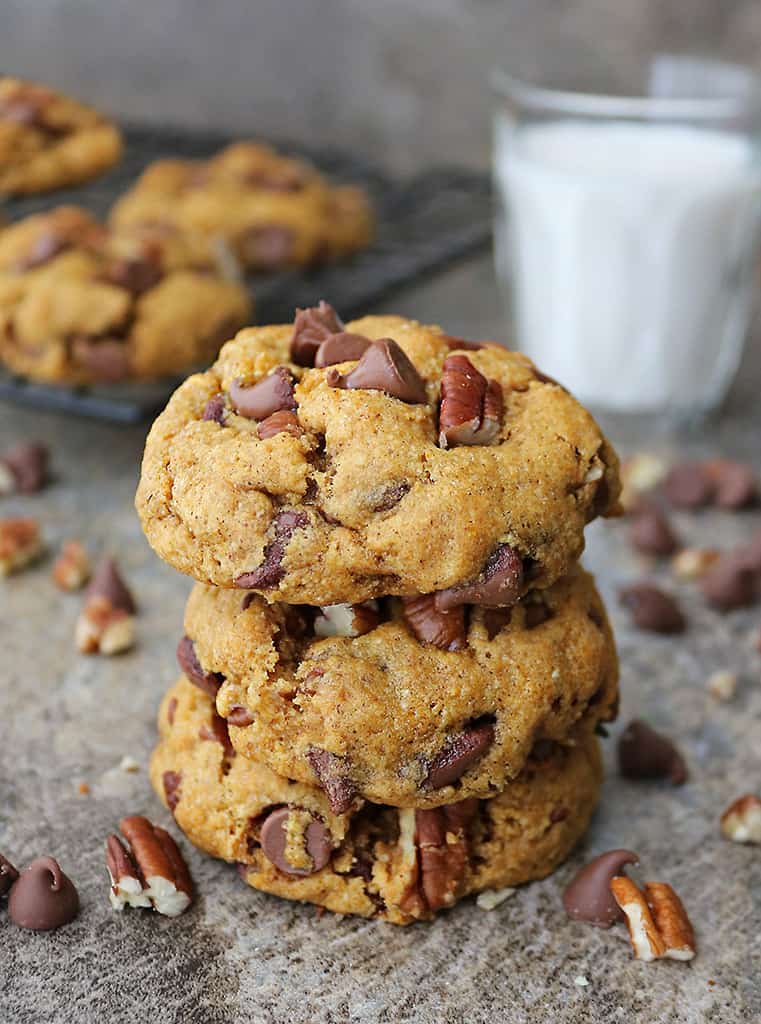 stack of 3 pumpkin chocolate chip cookies dairy-free with a glass of milk in the background.