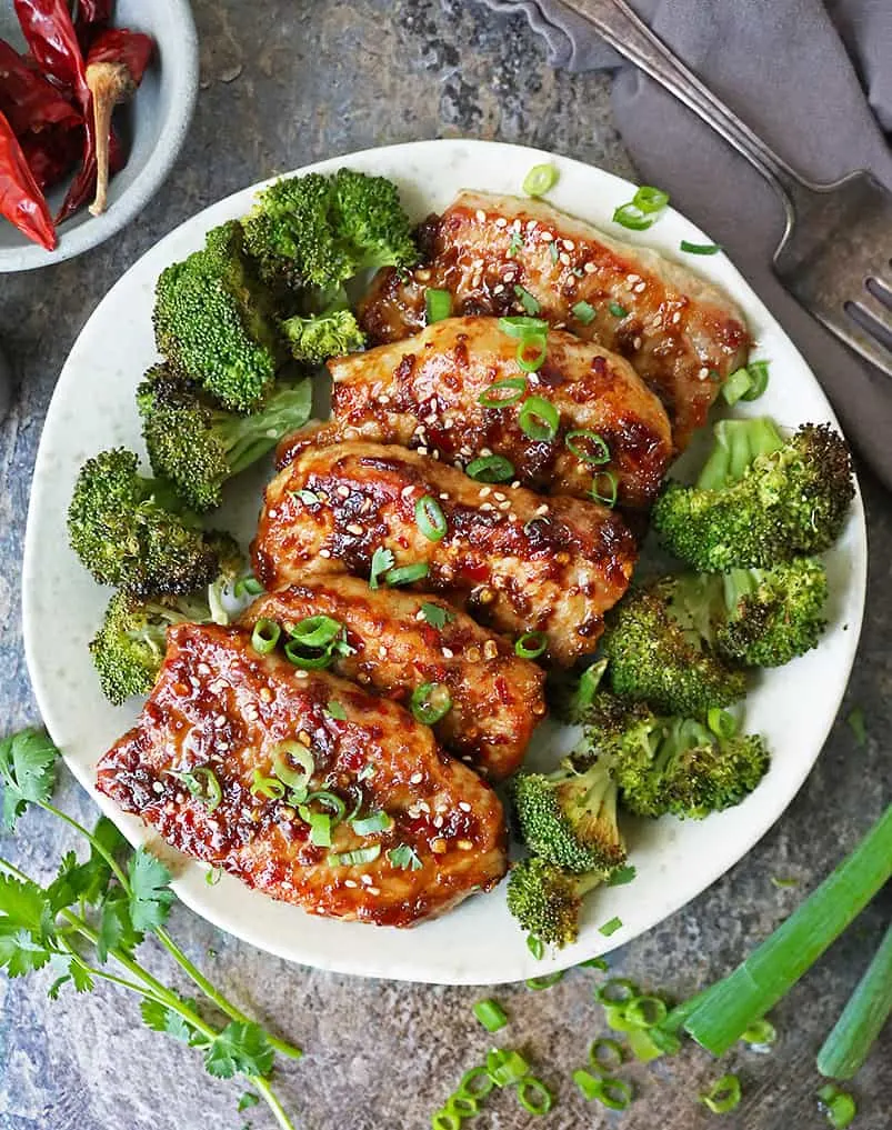 Boneless pork chops are pan sautéed and encased in a delicious ginger glaze and served on a plate.