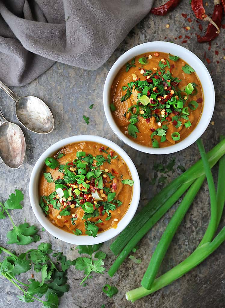 Two bowls of Thick creamy healthy pumpkin curry soup with all the toppings