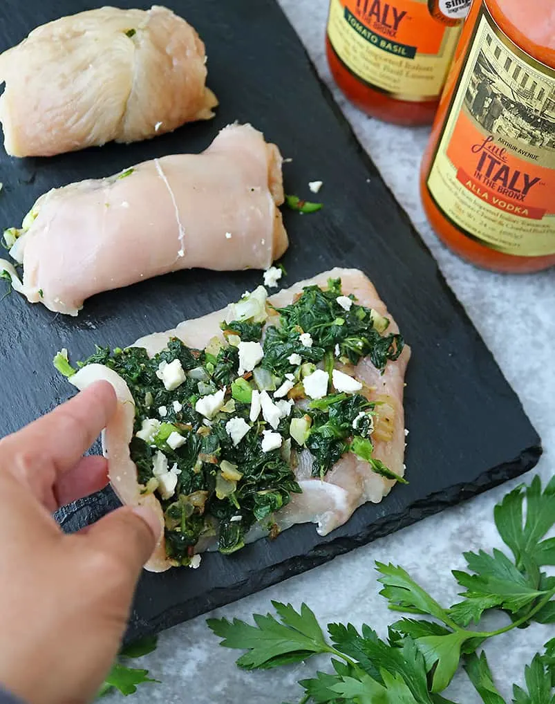 Rolling up chicken stuffed with spinach feta for Chicken Saltimbocca with a spin