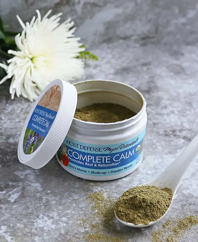 Host Defense Complete Calm Powder  with a flower in background