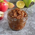 easy apple chutney in a glass container with apples in the background.