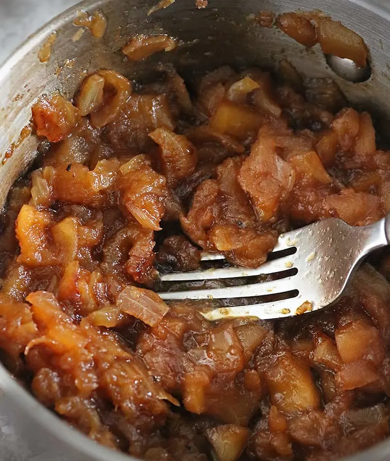 Mashing the pieces of apple to make apple chutney - in the pan.