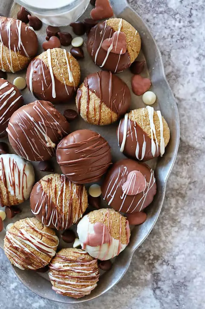 a plate of Almond Flour Peanut Butter Cookies dipped in chocolate with ruby chocolate hearts on some.