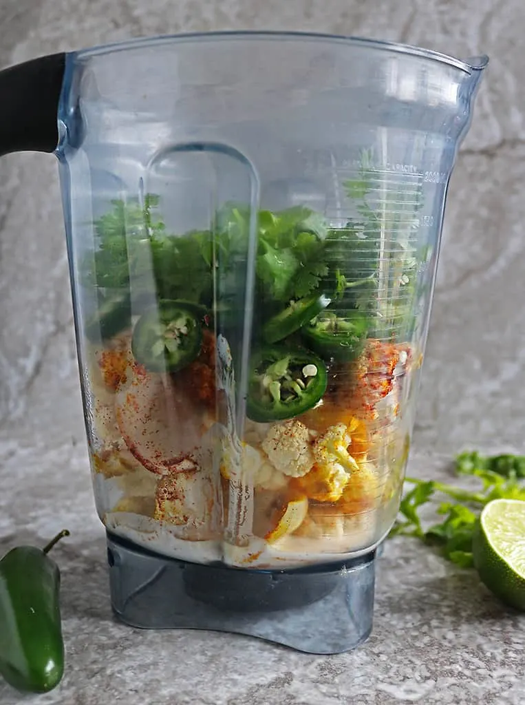 side view of blender showing Blending roasted ingredients together to make Cauliflower Jalapeno sauce