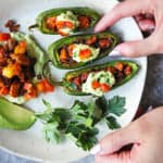 In this recipe for Keto Stuffed Jalapenos, jalapenos are stuffed with a spicy chicken stuffing, topped with an avocado cream, and bits of sauteed bell peppers, making for some delicious low carb snacking!