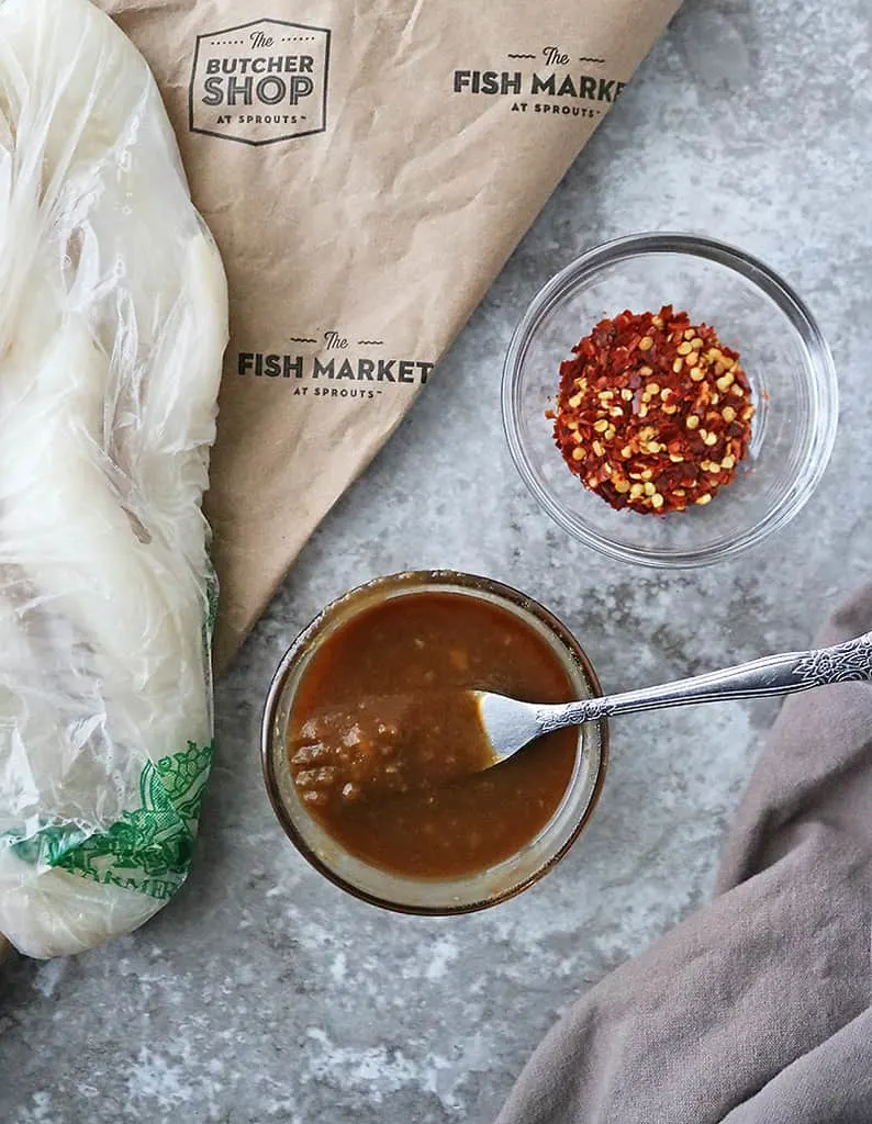 Delicious Easy Miso Glaze in a bowl with a bowl of chili flakes next to it and Cod from the Sprouts Fish Market lying adjacent as well.